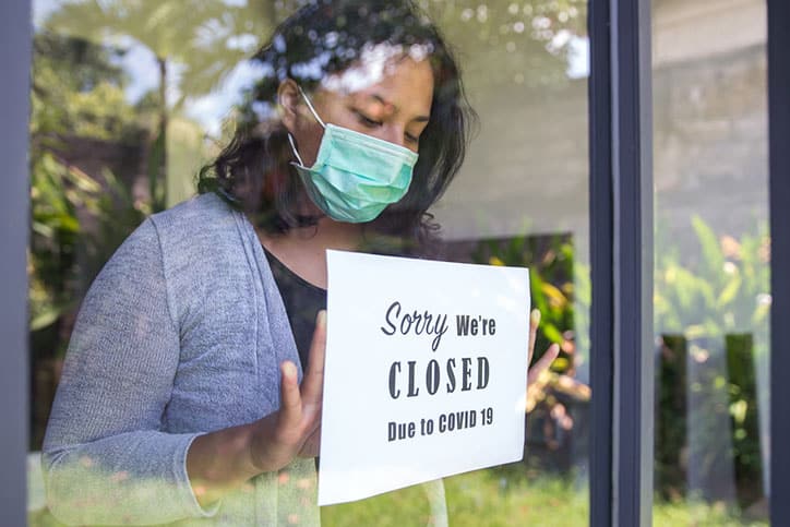 Woman closing business with sign.