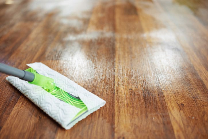 Closeup of mop on vinyl floor with wood grain appearance.