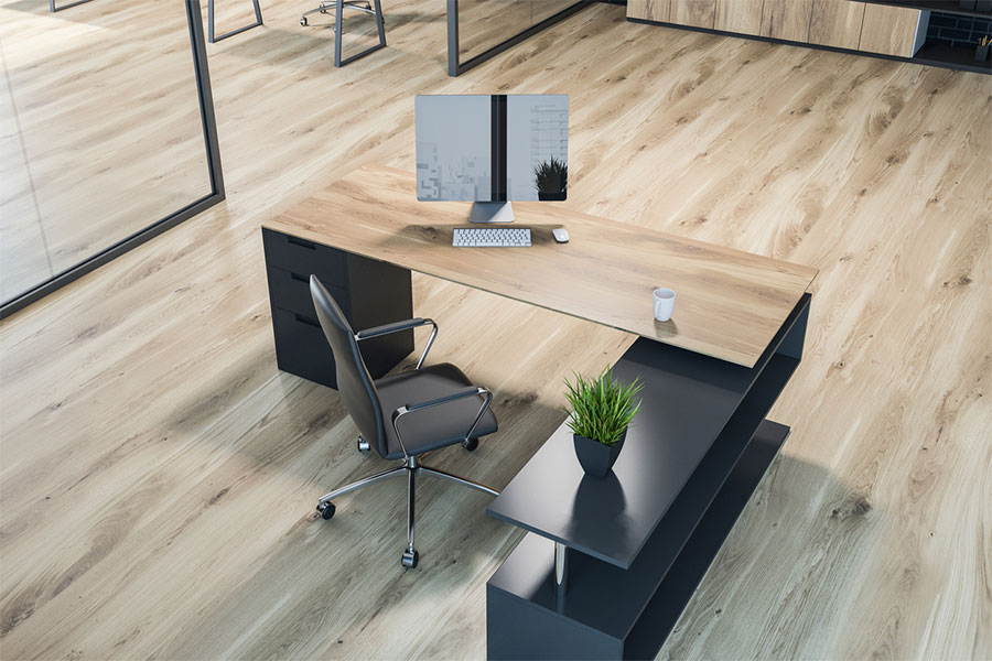 A modern office with a wooden desk, black chair, desktop computer, and coffee cup rests on a light wood floor—ideal for business owners who know that professional luxury vinyl cleaning is a smart investment for lasting workplace appeal.